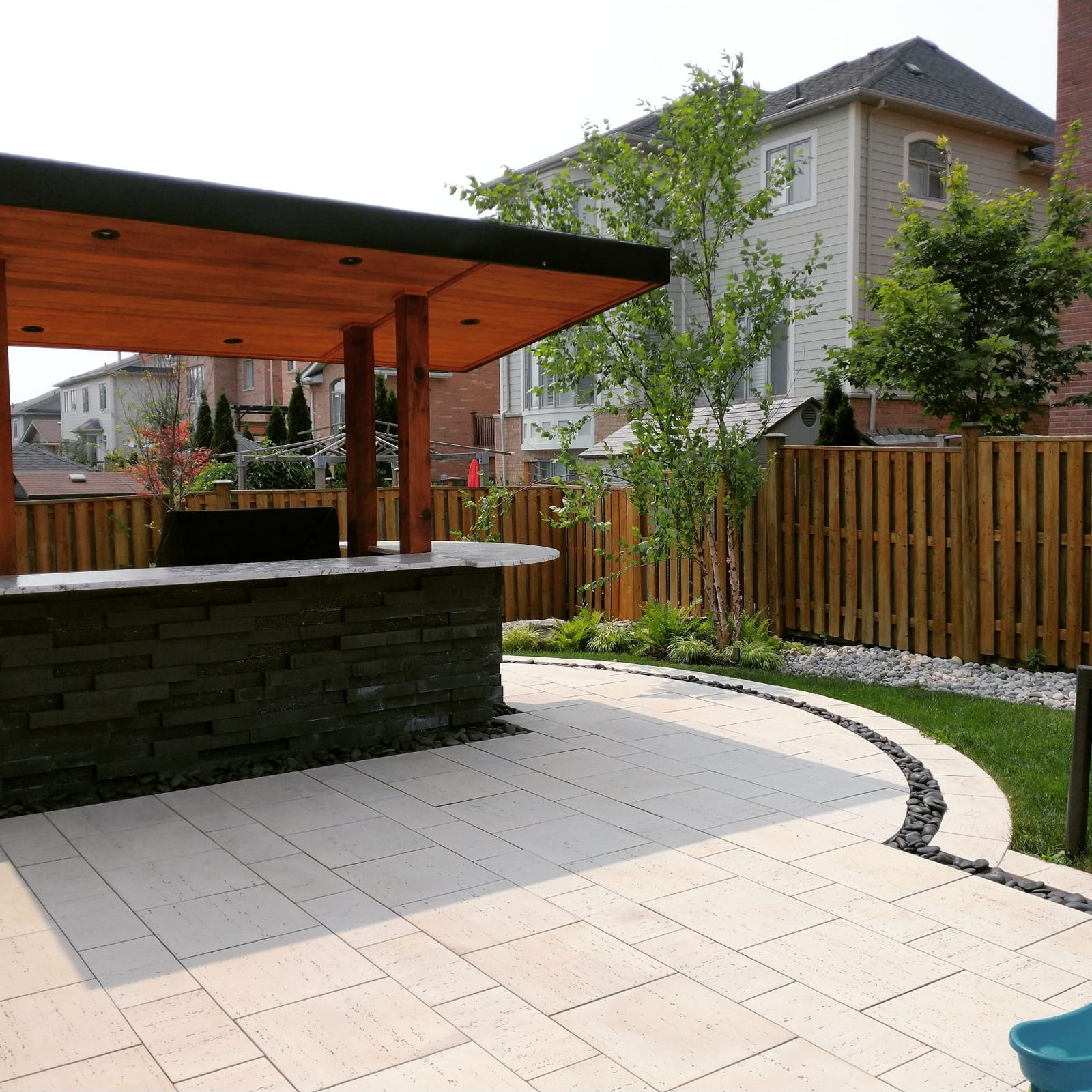 Covered outdoor bar with stone veneer on a large-format paver patio