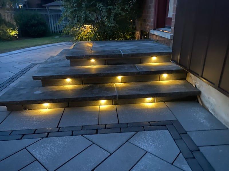 Paver walkway and steps with lit risers at night